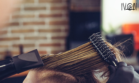 Hair stylist blow-drying and brushing hair in salon